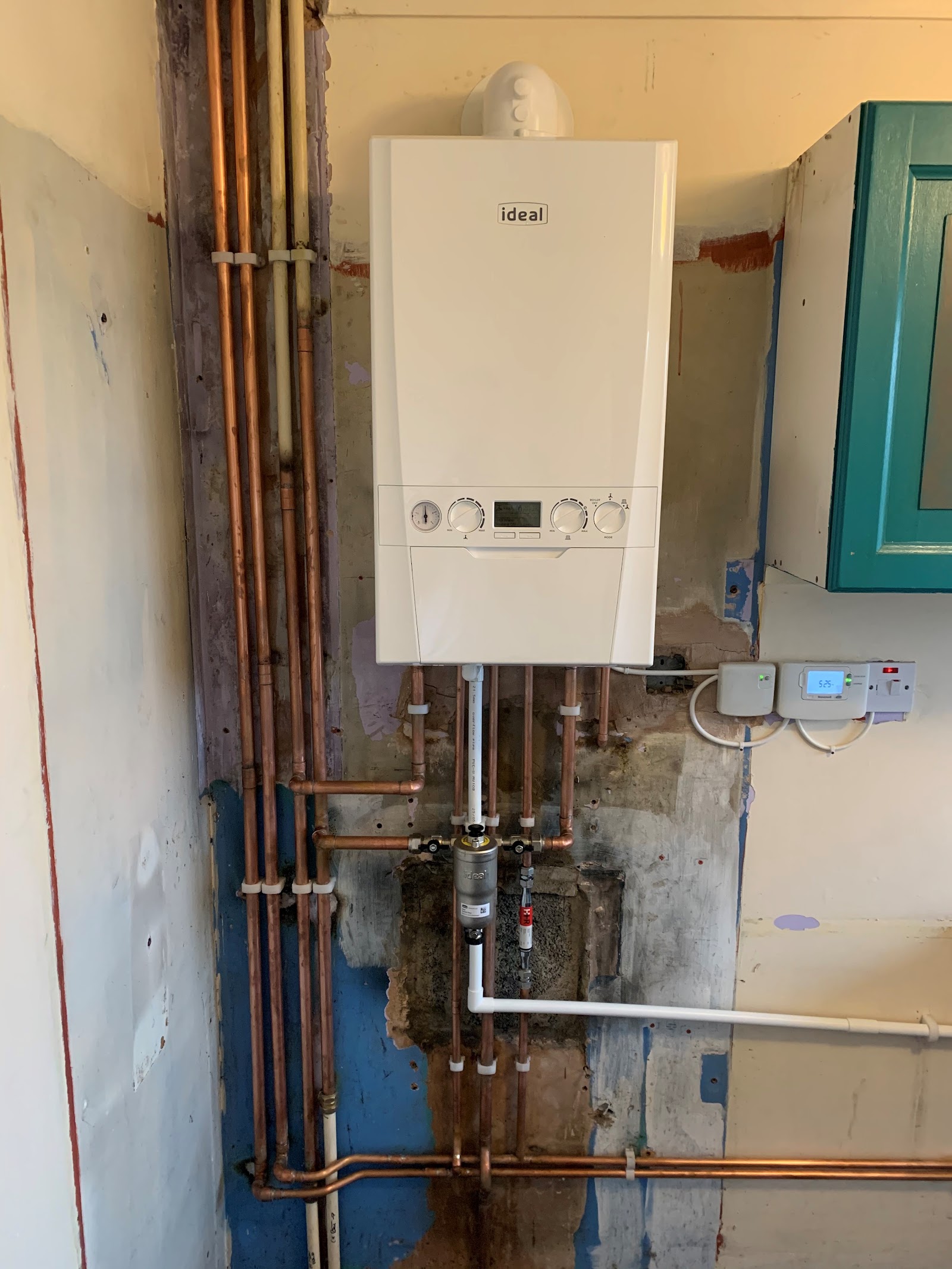 An Ideal boiler going in on a stripped wall, with several copper pipe runs